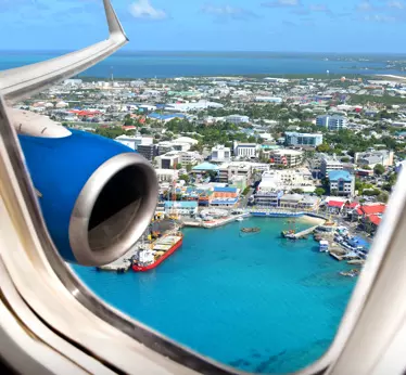 Airplane window seat view of Grand Cayman harbour, with clear skies and turquoise waters.